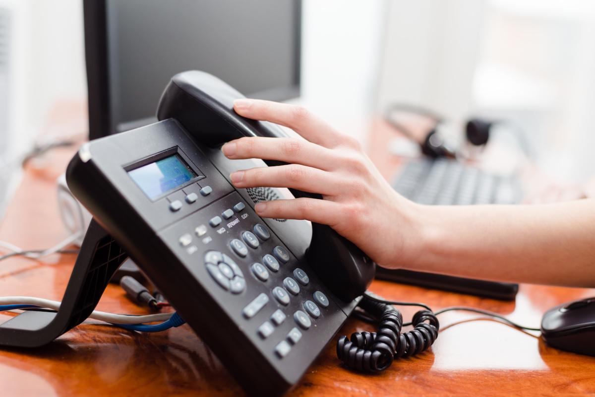 A hadn grabbing a desk phone